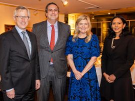 Four people in formal attire smiling at an indoor event.