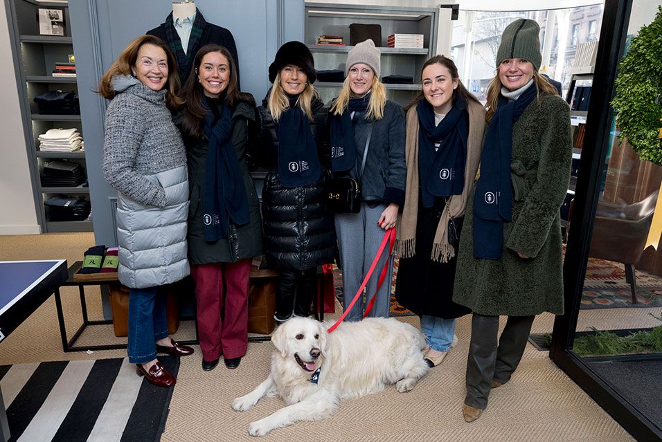 Six Society members standing inside a shop during Miracle on Madison. A large white dog is lying in front of them.